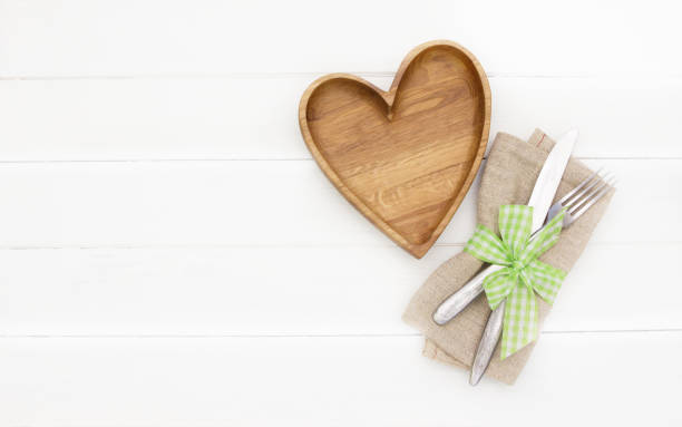 istock Place Setting. Empty wooden  plate, fork and knife on white  background.Wooden plate heart shape.Love food, love eating, romantic dinner , Valentine's day 1167402185