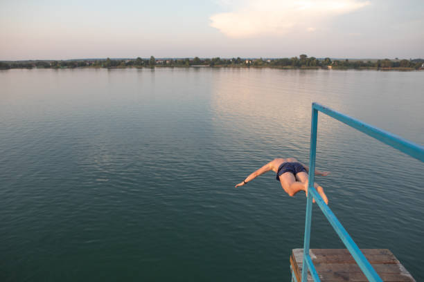 istock man jumping from tower at lake water on sunset 1167406606