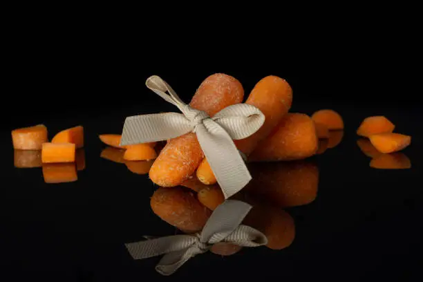 Photo of Orange baby carrot isolated on black glass