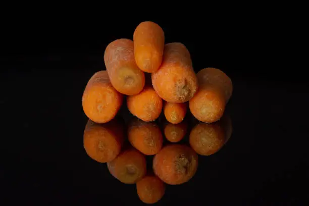 Photo of Orange baby carrot isolated on black glass