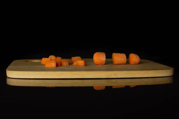 Photo of Orange baby carrot isolated on black glass