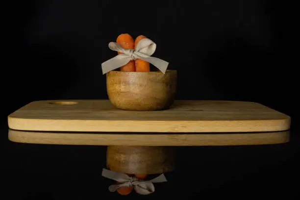 Photo of Orange baby carrot isolated on black glass