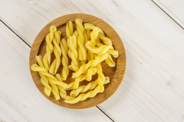 Raw pasta gemelli on grey wood Lot of whole raw pasta gemelli on bamboo plate flatlay on white wood bamboo twist stock pictures, royalty-free photos & images
