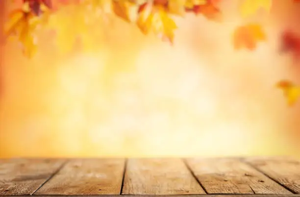 Wooden table and blurred Autumn background. Autumn concept with red-yellow leaves background.