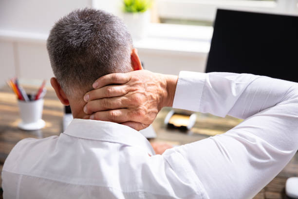 Businessman Suffering From Neck Pain Young Businessman Suffering From Neck Pain At Office ergonomics photos stock pictures, royalty-free photos & images