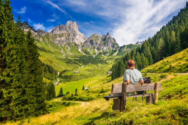 jeune homme s'asseyant sur le banc et apprécie la vue sur le grand bischofsmàtze, montagnes de dachstein, alpes - european alps women summer outdoor pursuit photos et images de collection