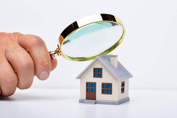 istock Person Hand With Magnifying Glass And Miniature House 1167413561