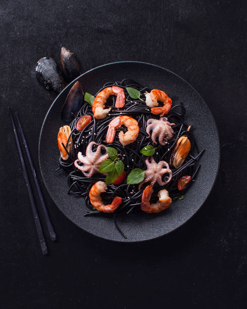 istock Modern Japanese dinner, Mediterranean cuisine. Black spaghetti ink black cuttlefish ink with seafood, shrimp, mussels, octopus on black background. The view from the top. Copy space 1167425629
