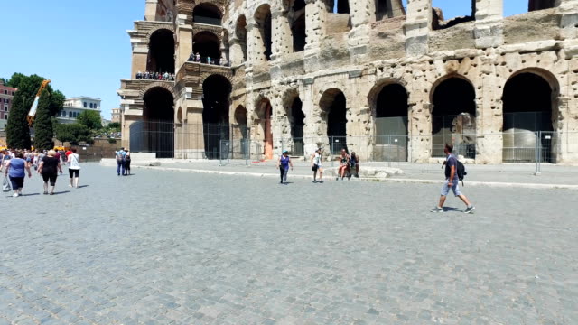 Moving POV on pavement near famous Colosseum amphitheater in Rome, slow motion