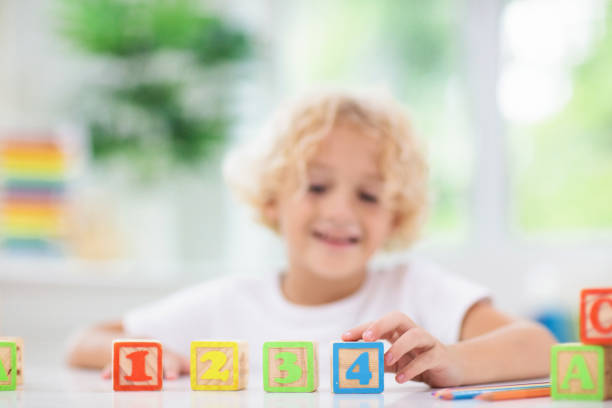 istock Child learning letters. Kid with wooden abc blocks 1167433222