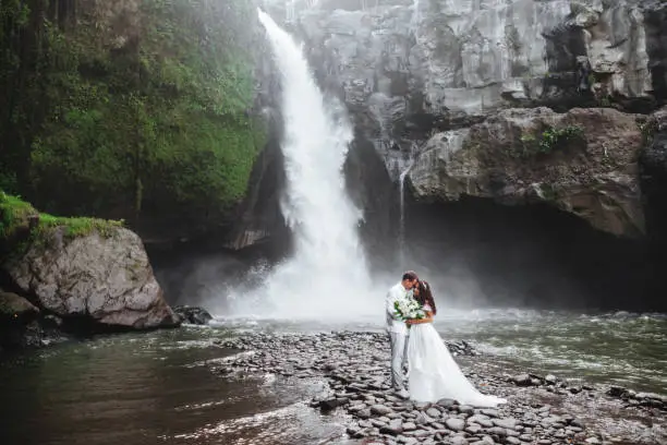 Photo of Young couple in love bride and groom, wedding day near a mountain waterfall.