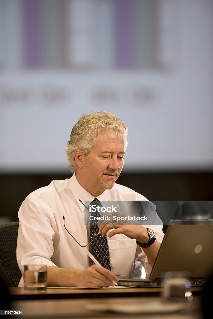 Attraenti Uomo d'affari che lavora alla sua scrivania - Foto stock royalty-free di Abbigliamento da lavoro