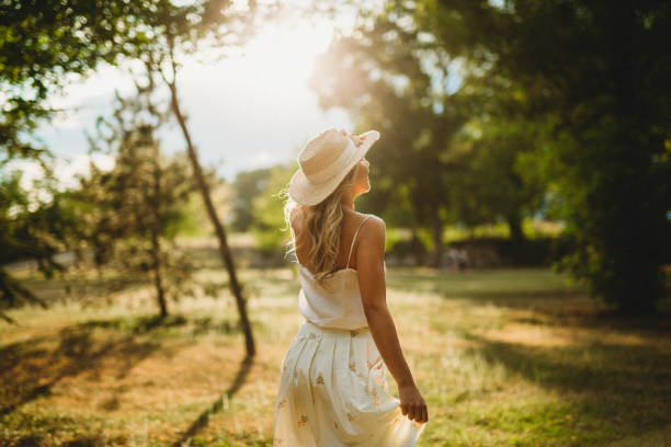beautiful young woman, latina college student walking in nature, surrounded by trees with a beautiful golden sunset in the background. girl with a serious face observing nature attentively.