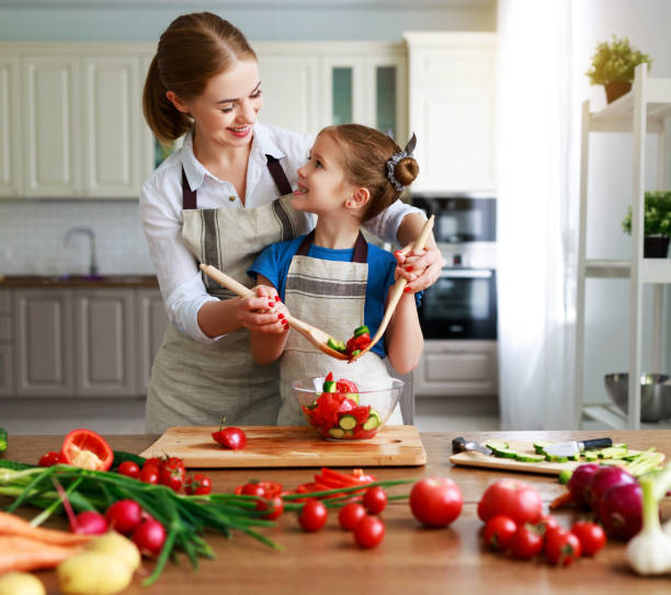 happy family mother with child girl preparing vegetable salad - family mother domestic life food imagens e fotografias de stock