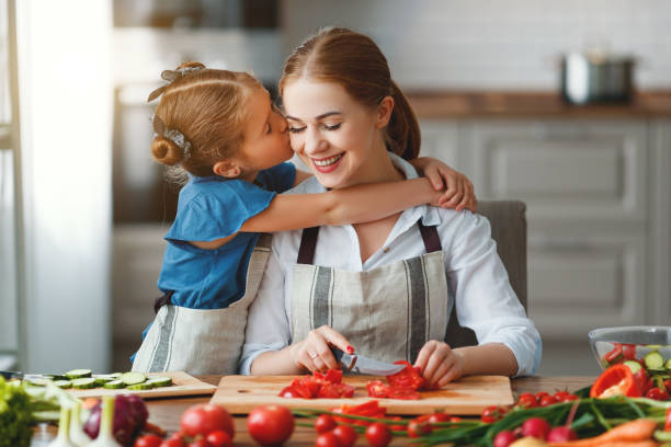 happy family mother with child girl preparing vegetable salad - family mother domestic life food imagens e fotografias de stock