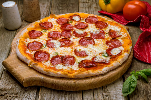 istock Pepperoni pizza on board on old wooden table 1167461405