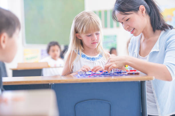 istock Young Asian Teacher Helping Female Caucasian Student 1167464396