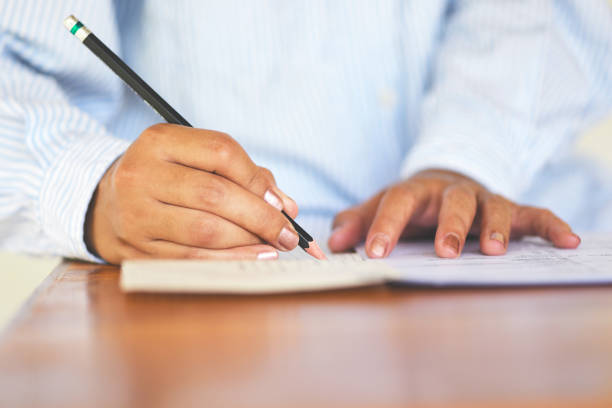 istock take the exam final high school university student holding pencil writing on paper answer sheet - education college in class taking notes sitting learning writing selected choice in examination room 1167473906