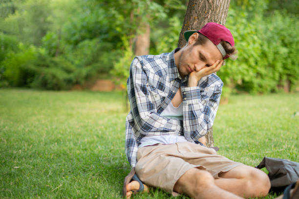 istock young male sleeping in the public park on the grass under the tree 1167480463