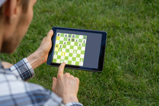 playing chess on a digital device outdoor, mental activity playing chess on a digital device outdoor, mental activity computer chess stock pictures, royalty-free photos & images