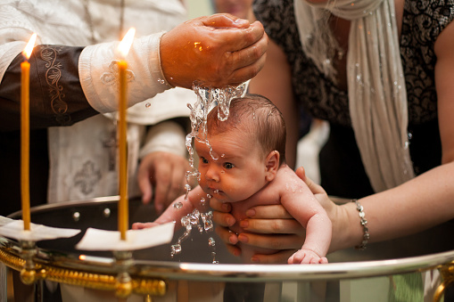 Bautismo de bebé recién nacido en agua bendita. bebé sosteniendo las manos de la madre. Bebé bañarse en agua. Bautismo en la fuente photo