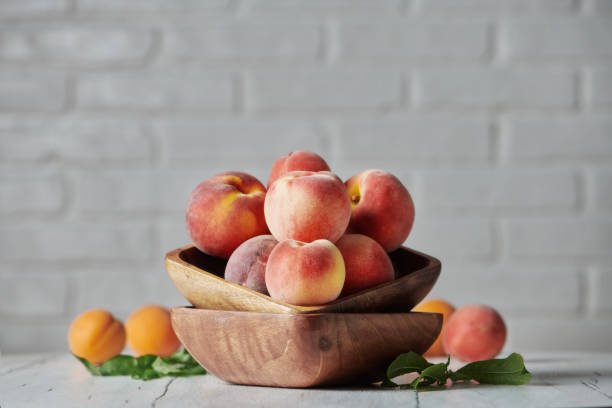 istock Peaches in wooden bowl with white brick wall background 1167492060