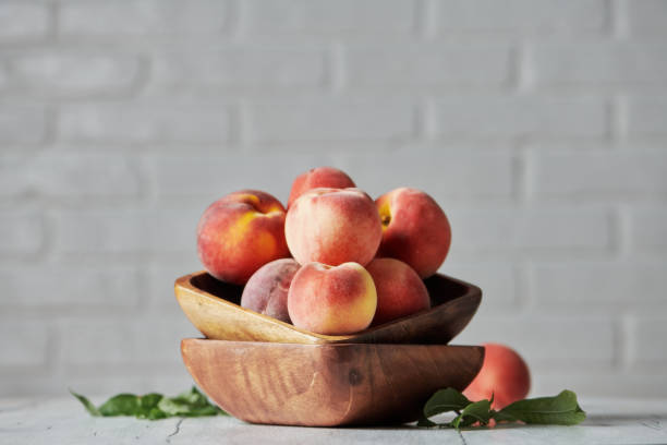 istock Peaches in wooden bowl with white brick wall background 1167492094