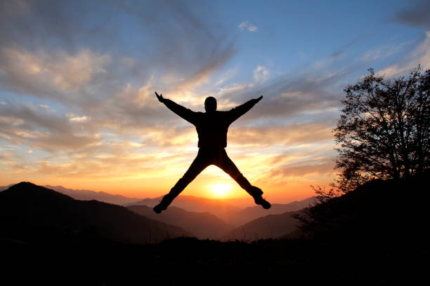 istock silhouetted man jumping on mountain top looking at view 1167496913