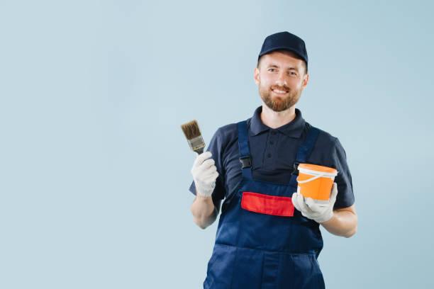 istock Cheerful service worker with paint can and brush in hands dressed in uniform 1167502042