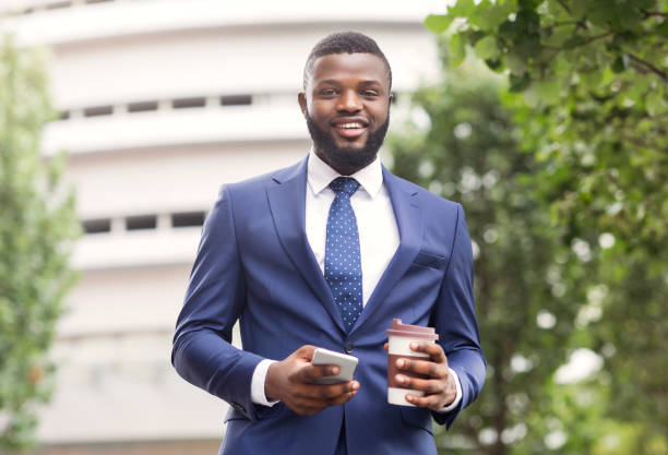 istock Cheerful african employee having coffee break and using smartphone outdoors 1167505350