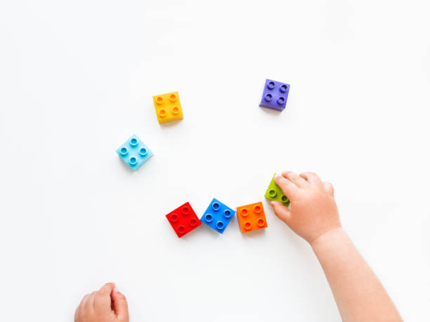 istock Child is playing with colorful constructor blocks. Kid's hands with bricks toy on white background. Educational toy, flat lay, top view. 1167505636