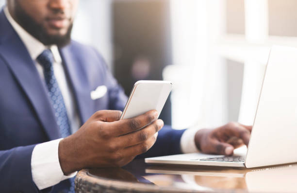 istock Afro Businessman Using Cellphone And Laptop Working In Outdoor Cafe 1167505652