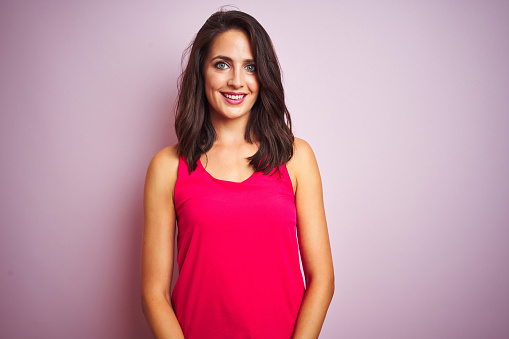 Young beautiful woman wearing t-shirt standing over pink isolated background with a happy and cool smile on face. Lucky person.