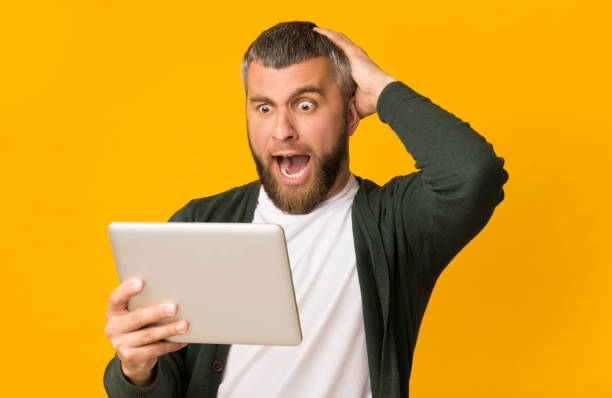 istock Impressed bearded man holding tablet and touching his head 1167513918
