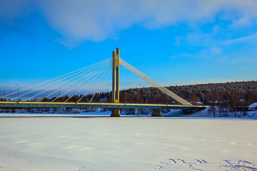 Snowy winter in the Arctic, Rovaniemi. Magnificent String Bridge through the frozen river of Kemijoki
