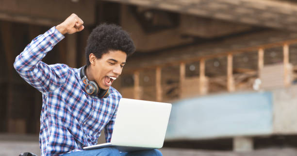 I did it. Young guy celebrating his university entrance I did it. Young guy celebrating passing entrance exams checking list of students online on laptop, panorama with copy space school test results stock pictures, royalty-free photos & images