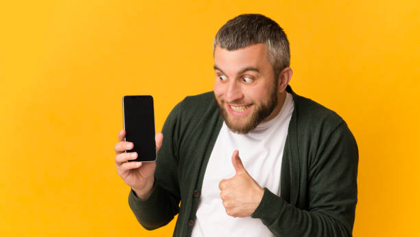 istock Super happy bearded man holding smartphone, showing thumb up 1167514203
