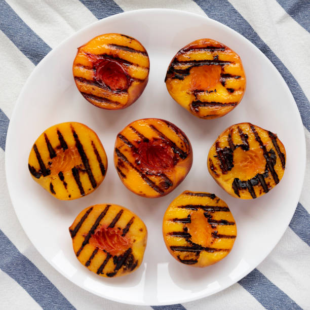 istock Homemade grilled peaches on a white plate, overhead view. Flat lay, top view, from above. 1167515425