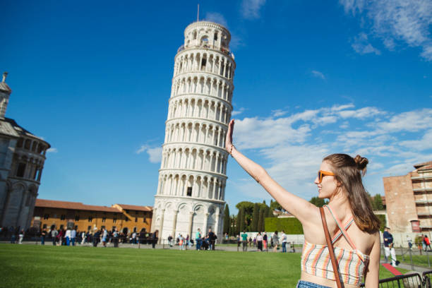 Discovering Historic Italy A woman is gesturing with her hands in front of the Leaning Tower of Pisa. pisa stock pictures, royalty-free photos & images
