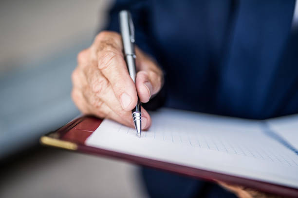Senior businessman writing a business strategy in notebook.