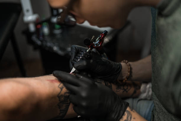 istock Tattoo artist making tattoo on customer's leg 1167518398