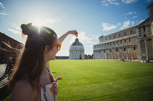 Portrait of beautiful 30s girl using paper map near tower in Pisa in Italy. Happy vacations in Italy. Stylish woman visiting Italian landmarks. Concept of travel