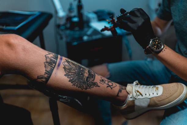 istock Tattoo artist making tattoo on customer's leg 1167519682