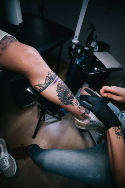 istock Tattoo artist making tattoo on customer's leg 1167519734