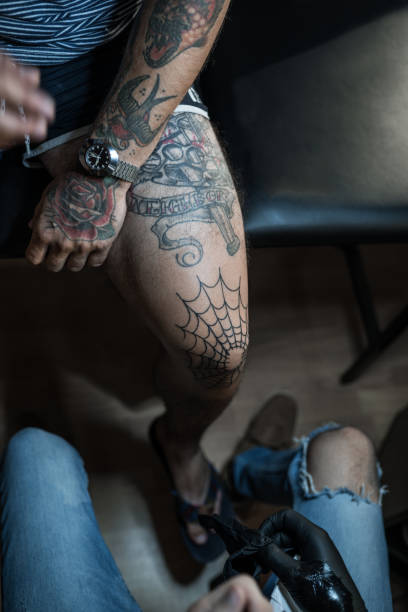Tattoo artist making tattoo on customer's leg