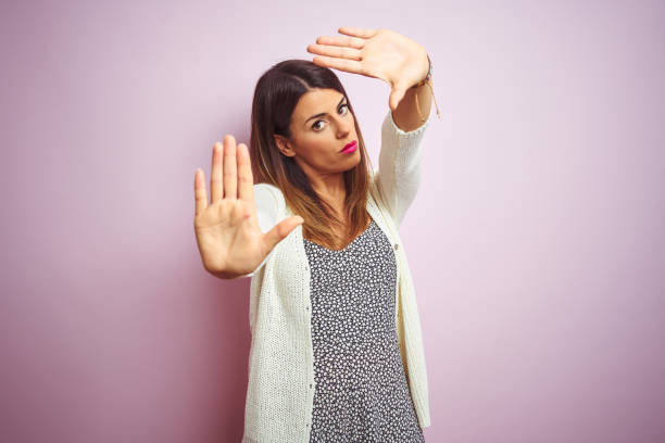 istock Young beautiful woman standing over pink isolated background doing frame using hands palms and fingers, camera perspective 1167520061