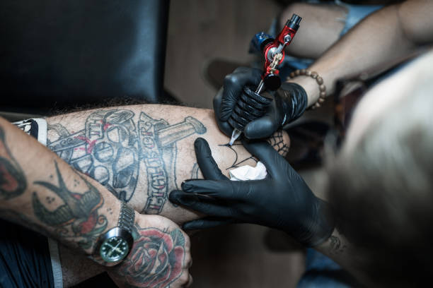 istock Tattoo artist making tattoo on customer's leg 1167521415