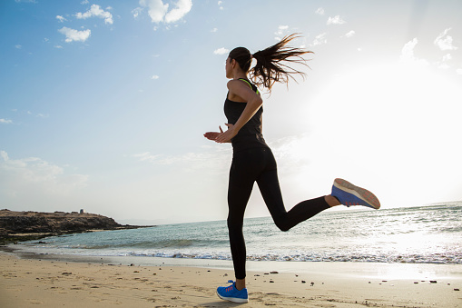 Sporty girl is running on the beach.