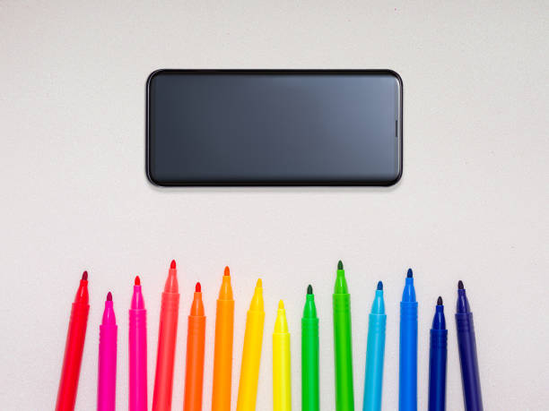 Felt tip pens and smartphone on shiny white background.
