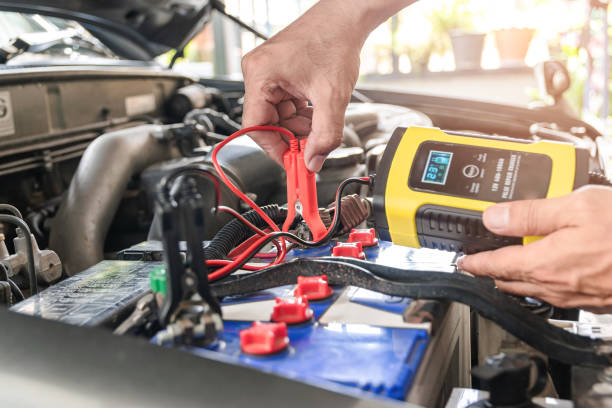 Car battery charger The car mechanic is using a voltage measuring instrument and charging the battery, the car's battery power. battery charger stock pictures, royalty-free photos & images